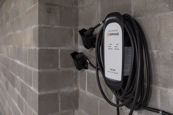 A black Enphase charger plugged into a wall socket.